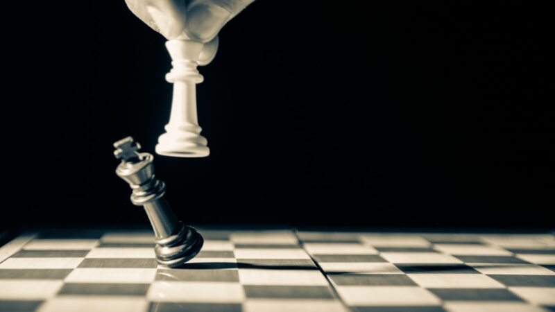 Chess strategy vs tactics - golden king piece on dark chessboard